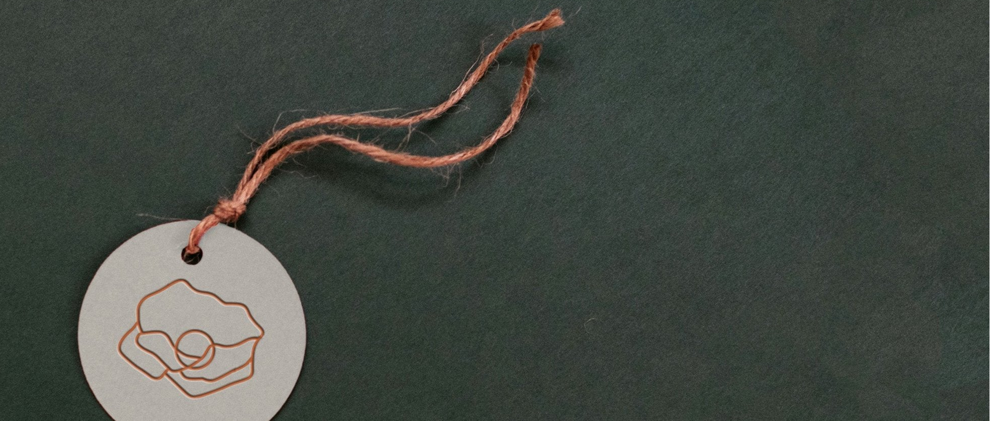 Round white tag with a copper poppy flower outline on a dark green background